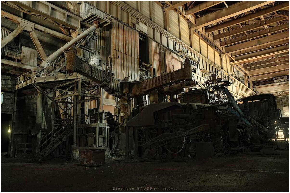 Real electric arc furnace with three graphite electrode arms raised for scrap charging