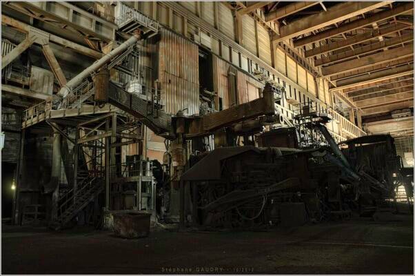 Real electric arc furnace with three graphite electrode arms raised for scrap charging
